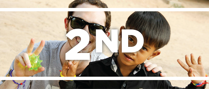 White text reads 2nd overlaying a photo of a male Miami student posing for a picture with a small international boy