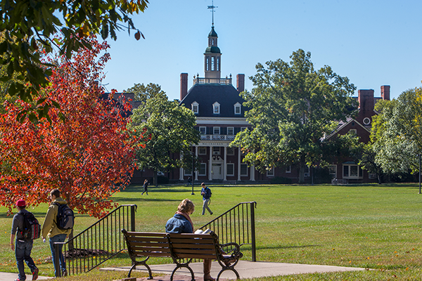 a student sitting on a bench outside with McCracken Hall in the background