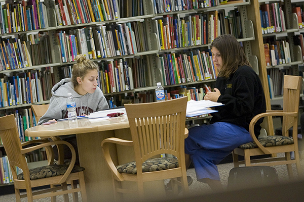 Two students working at a table in a library