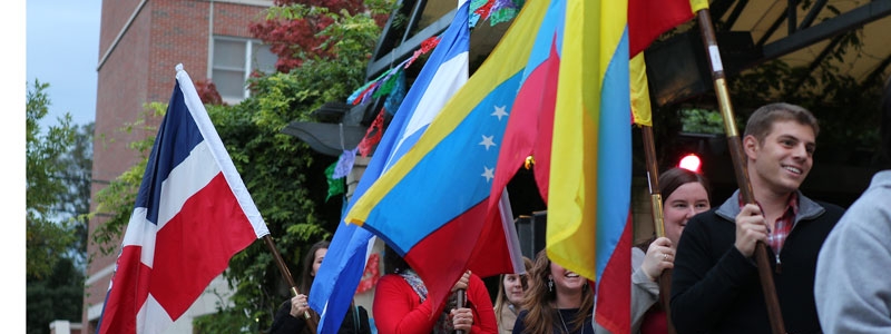 International Students with Flags, students walk in a parade while carrying the flags