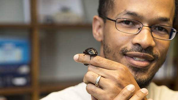  Grad student holding large species of cockroach native to South America.