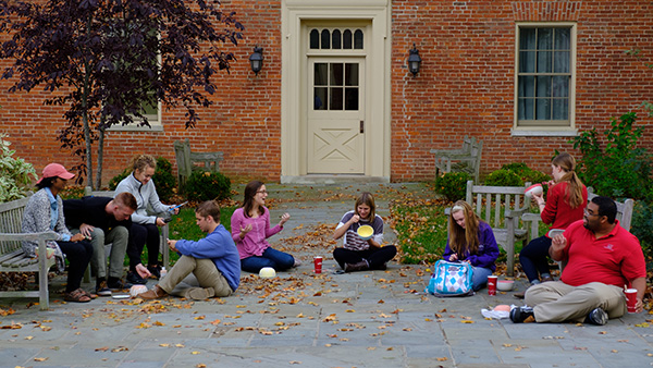  Group of students sitting outside painting pottery bowls.