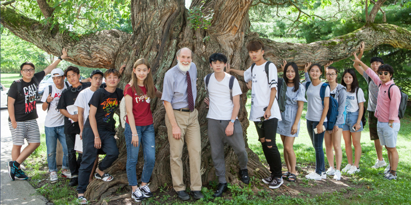 Instructor and students around tree