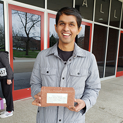 Axhay Patel holding his decorative brick he received for placing in the 5k race.