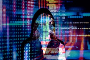 An image of a woman standing in front of a projected wall of code.
