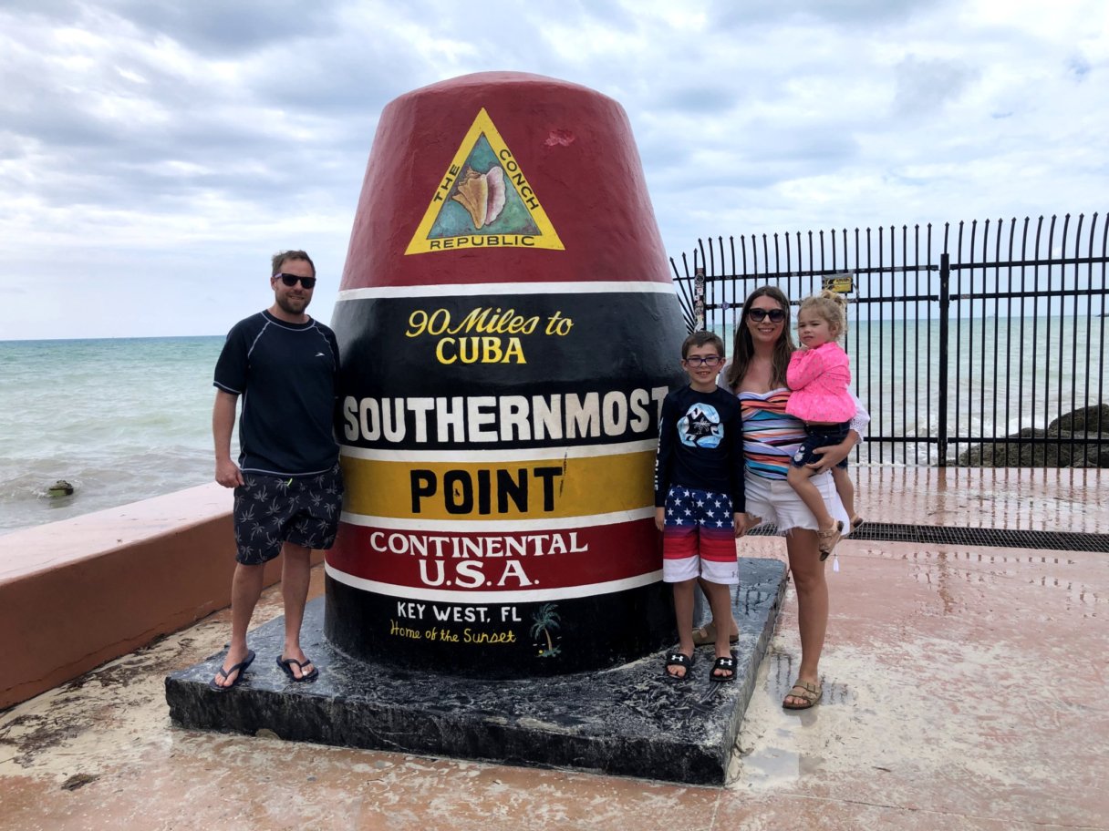 Nick Laes stands with his family next to a sign that states it is the southernmost point in the continental US
