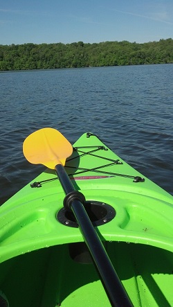POV from a yellow kayak in a lake, with blue sky above