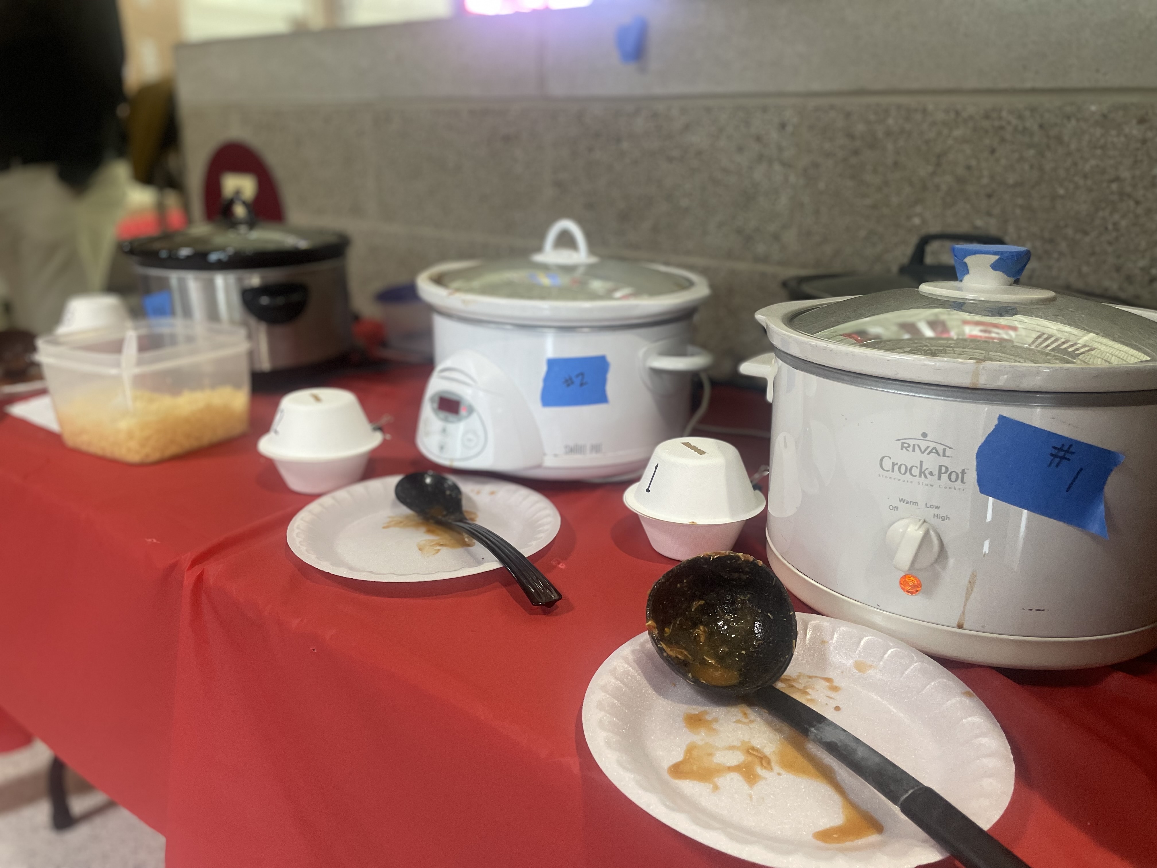 Crock pots full of chili with ladles on plates in front