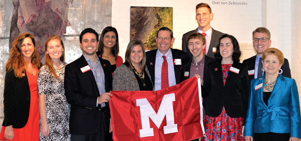 The Miami University Cleveland Alumni Board holding a Miami flag with President Hodge