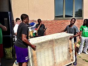 Incoming students and football players (l-r front) TJ Williams and Bert Birdsall and (l-r back) Carson Hicks, Buchi Okafor and Falon Lee moved donated furniture and clothes for the Family Resource Center.