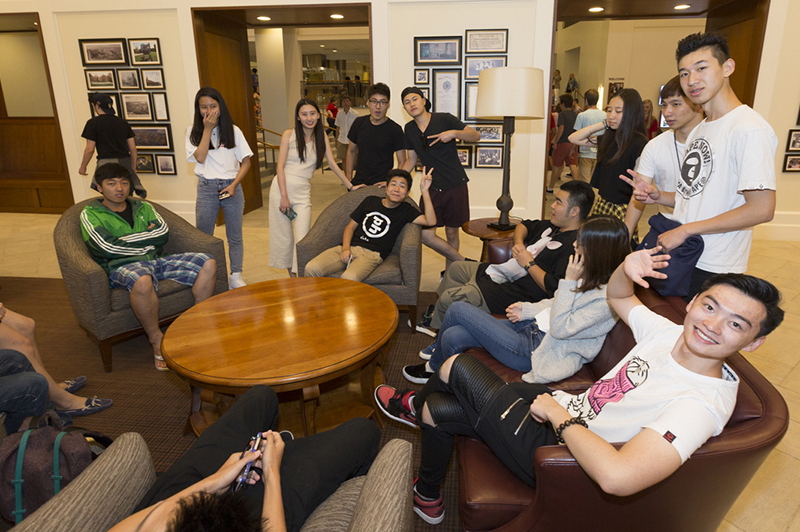 A large group of students converse on chairs and couches in Armstrong
