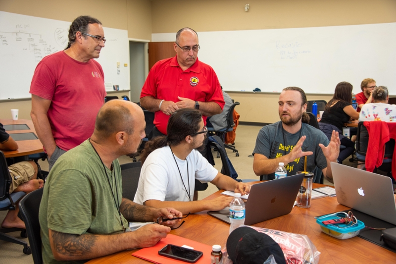 Myaamia Center Executive Director Daryl Baldwin (standing, left) and Miami Tribe of Oklahoma Chief Douglas Lankford (standing, center) listen as Jerome Viles, a development trainer for National Breath of Life Archival Institute for Indigenous Languages (National BoL), assists participants at a 2019 National BoL conference.
