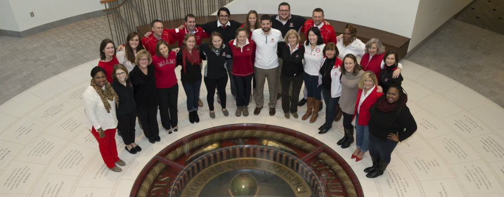 A group of admissions staff stand in a semicircle around the Miami seal in the floor of Armstrong Student Center