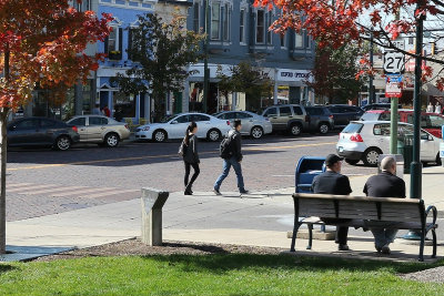 Students walking across street in Uptown Oxford. Two men sitting on a bench.