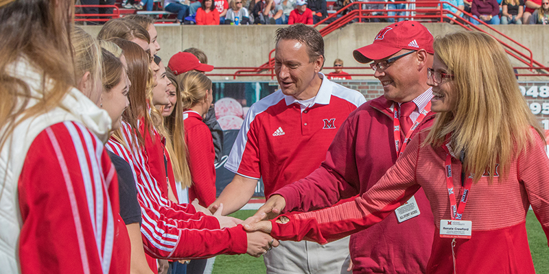 Greg and Renate Crawford high five students on the football field