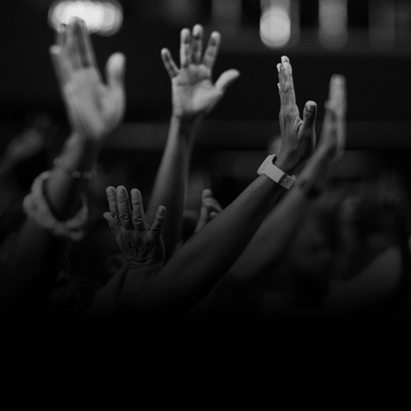 A black and white photo of hands reaching up