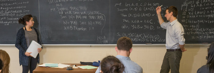 Professor at equation-covered board in a mathematics class