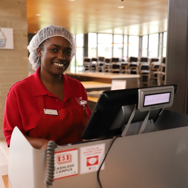  A dining employee smiling for a photo at a cash register.