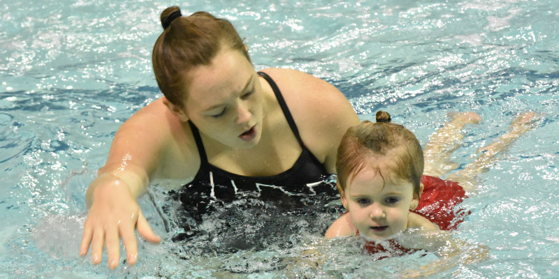 Instructor teaching child how to swim