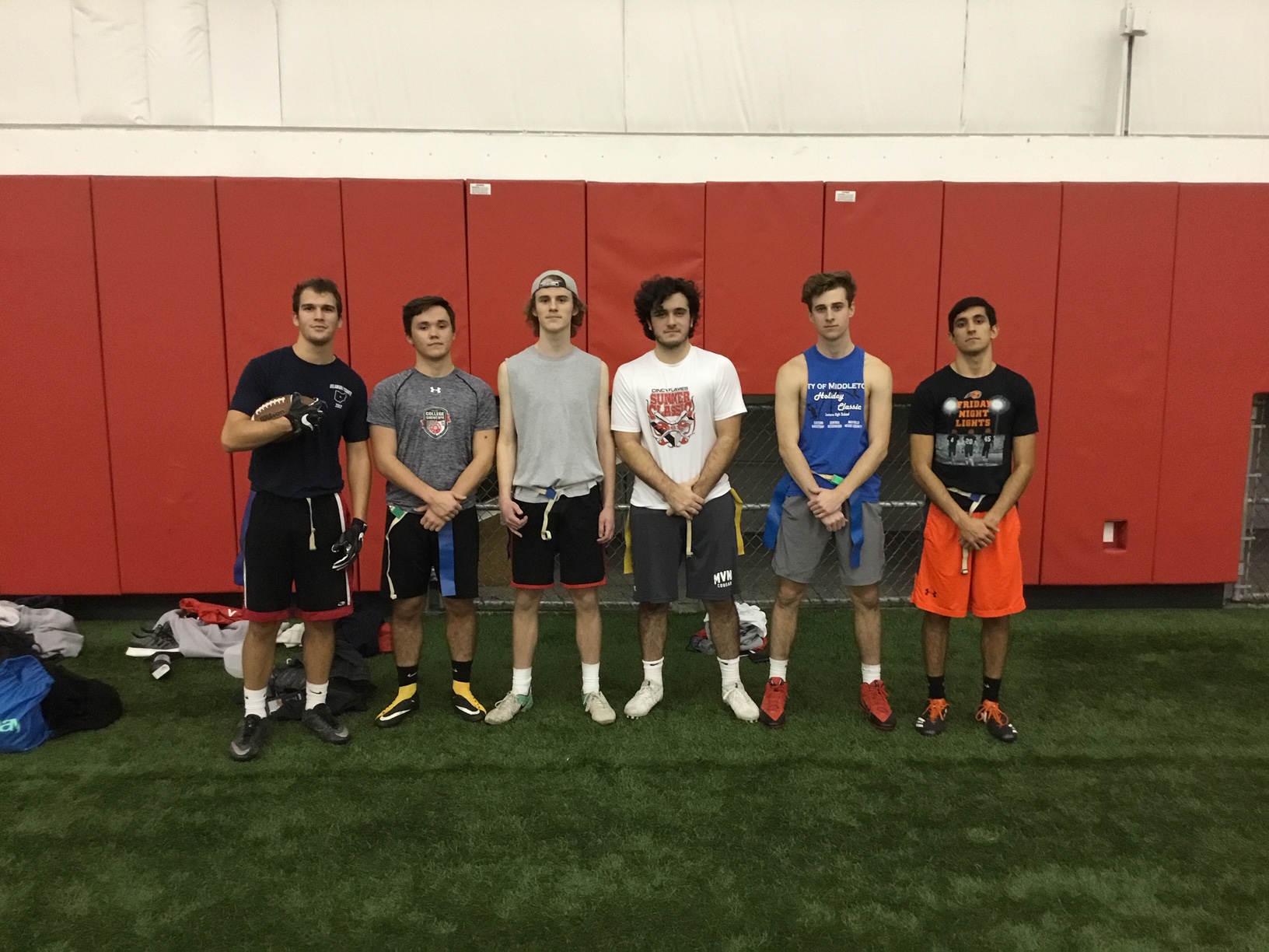 Arena Football runner up team poses on the indoor field with hands clasped at their waist wearing shirts and gym shorts.