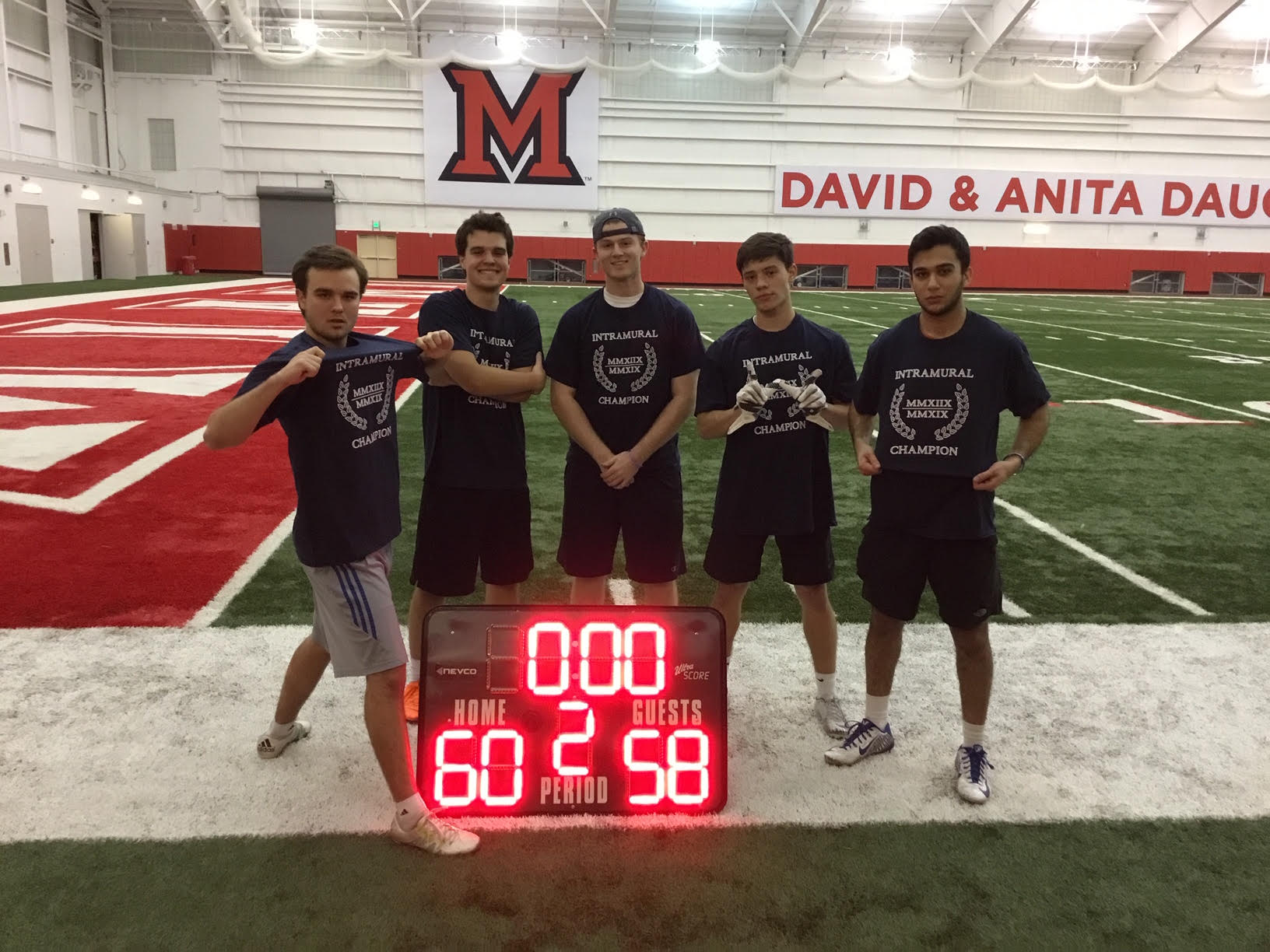 Arena Football champions pose on the indoor field wearing their Intramural Champions shirts.