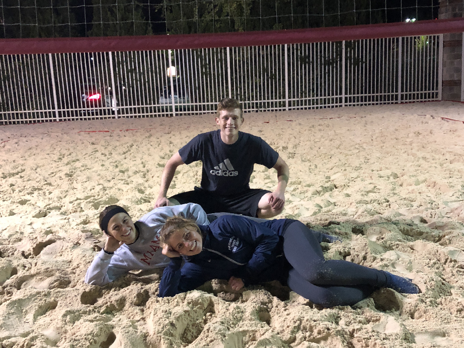 Sand volleyball runner up team poses together on the sand volleyball court.