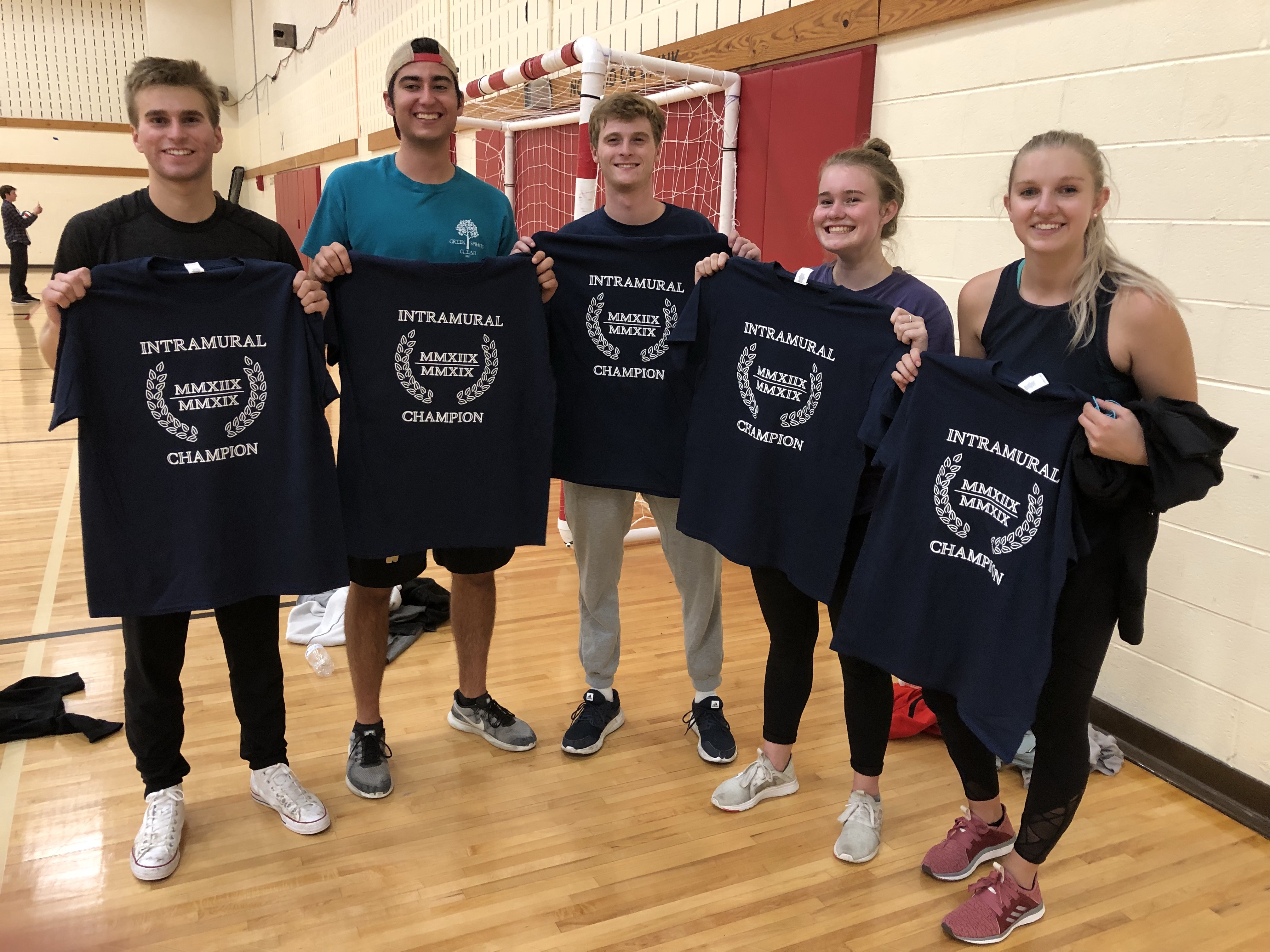 Indoor volleyball champions pose holding their Intramural shirts.