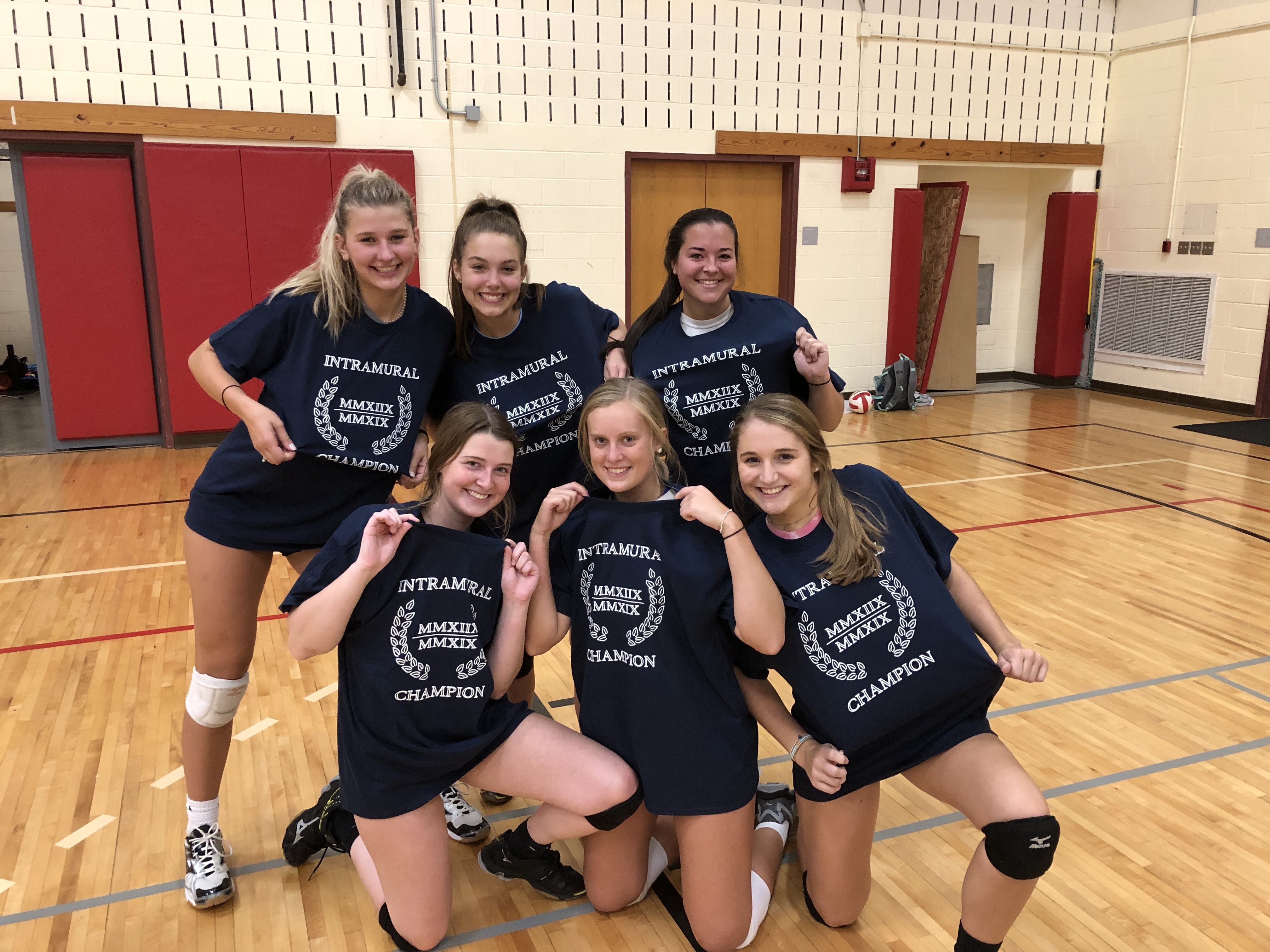 Women's volleyball league champion team poses together wearing their intramural shirts.