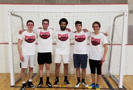 Fraternity League indoor soccer team champions pose in front of the goal in their intramural champion shirts.
