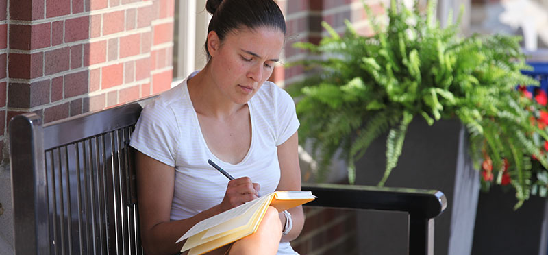 Teacher journaling outside on a bench