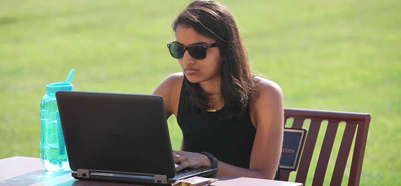 Teacher outside at a sunny table with a laptop