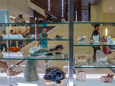 Students walk by mineral specimens in display case in Shideler Hall lobby.