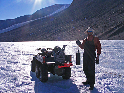 A student carries a sample from an Antarctic lake.