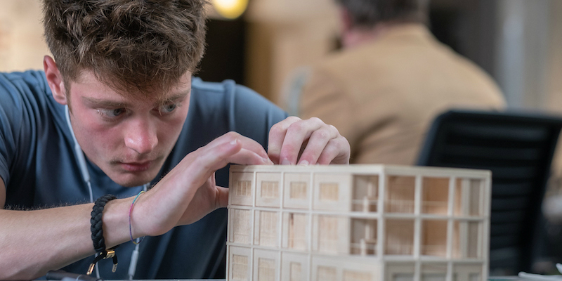 close up image of male student working on his building model