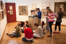 Students sit on gallery floor as they study an artwork