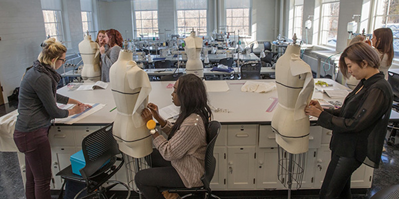Fashion students pin patterns to dressmakers mannequins in the classroom