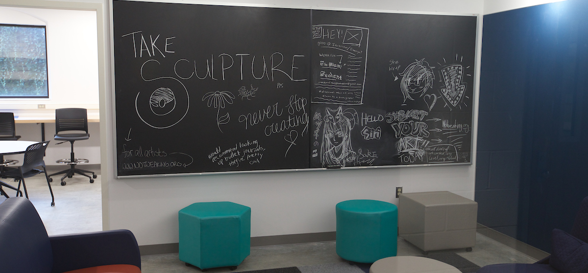 A lobby seating area in the Art Building. A chalkboard with doodles and slogans is visible.