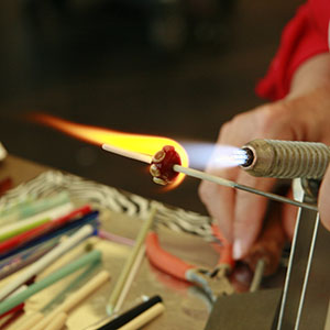A torch is used to shape a glass bead