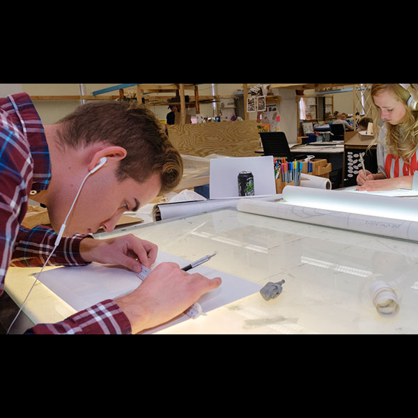 Two architecture students work opposite each other on projects on drafting boards