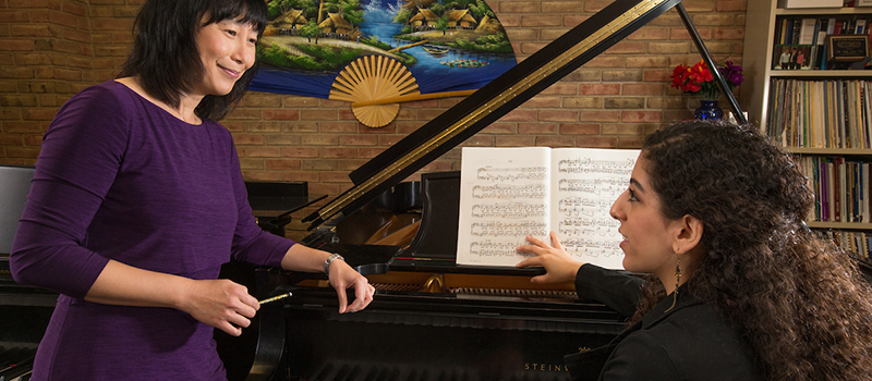  Dr. Tan speaks with her student as she conducts a piano lesson