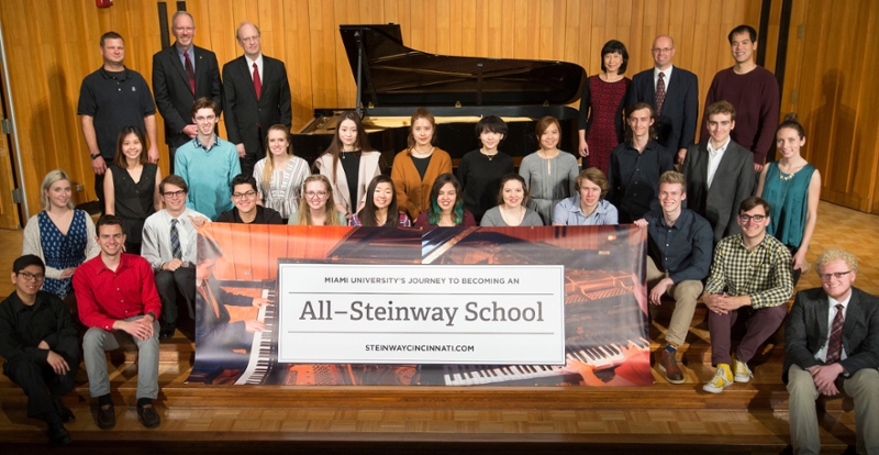 Department of Music piano faculty with students displaying a banner as Miami journeys to become an All Steinway School.