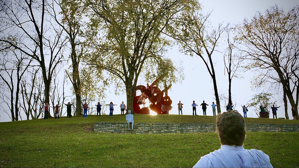 Outdoor scene with actors playing hippies on a hill at sunrise