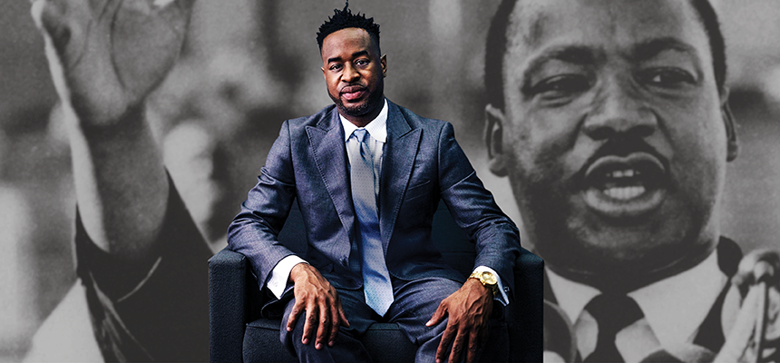 Damien Sneed sits in front of a large image of Martin Luther King