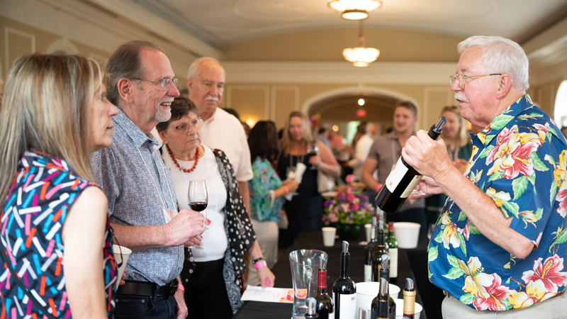  Jack Keegan speaks with a rapt group of attendees about a particular bottle of wine from the Premium Pour area