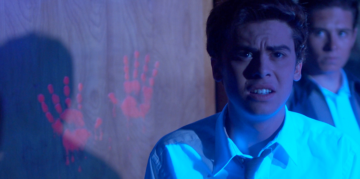 A man discovering ghostly handprints on a door from a production of Echoes of Miami