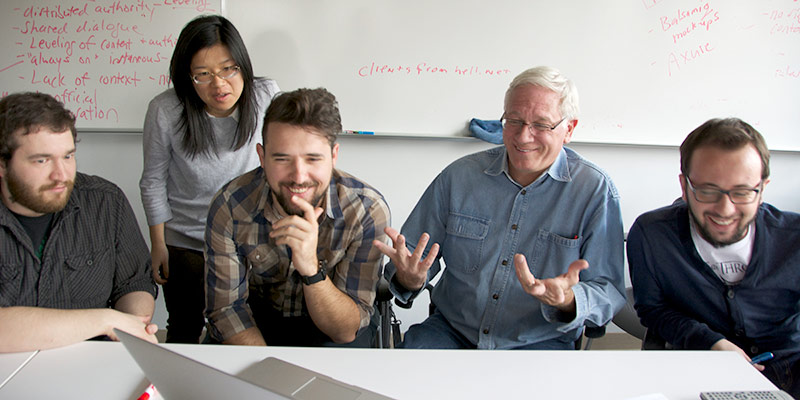  Ron Hall and students looking at a computer screen in the studio
