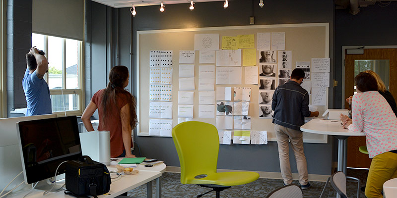 students in a studio looking at work pinned to a wall