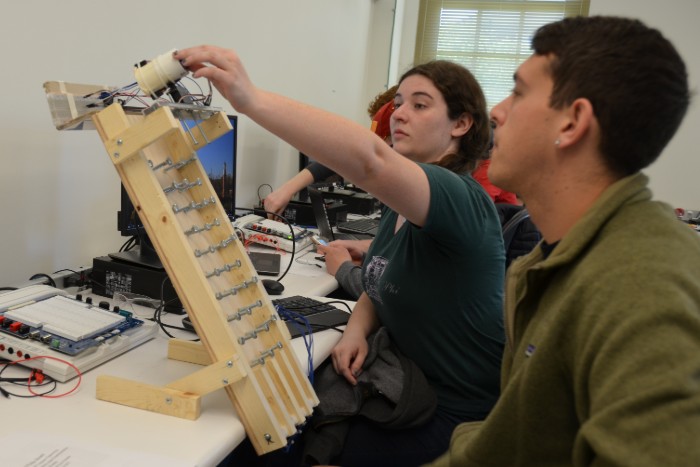 Two students working on a plinko-like construction