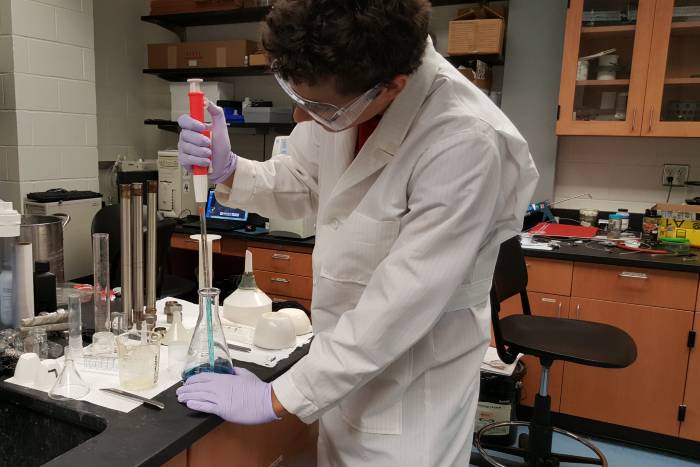 A male student transferring liquid from a beaker 