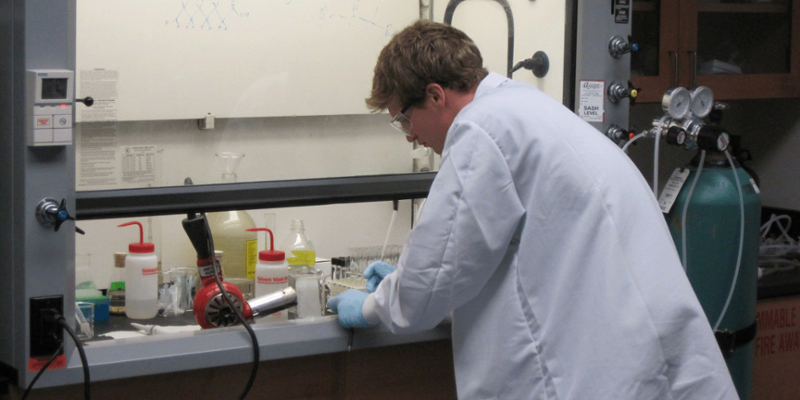 Student in a chemical engineering lab wearing a lab coat and goggles